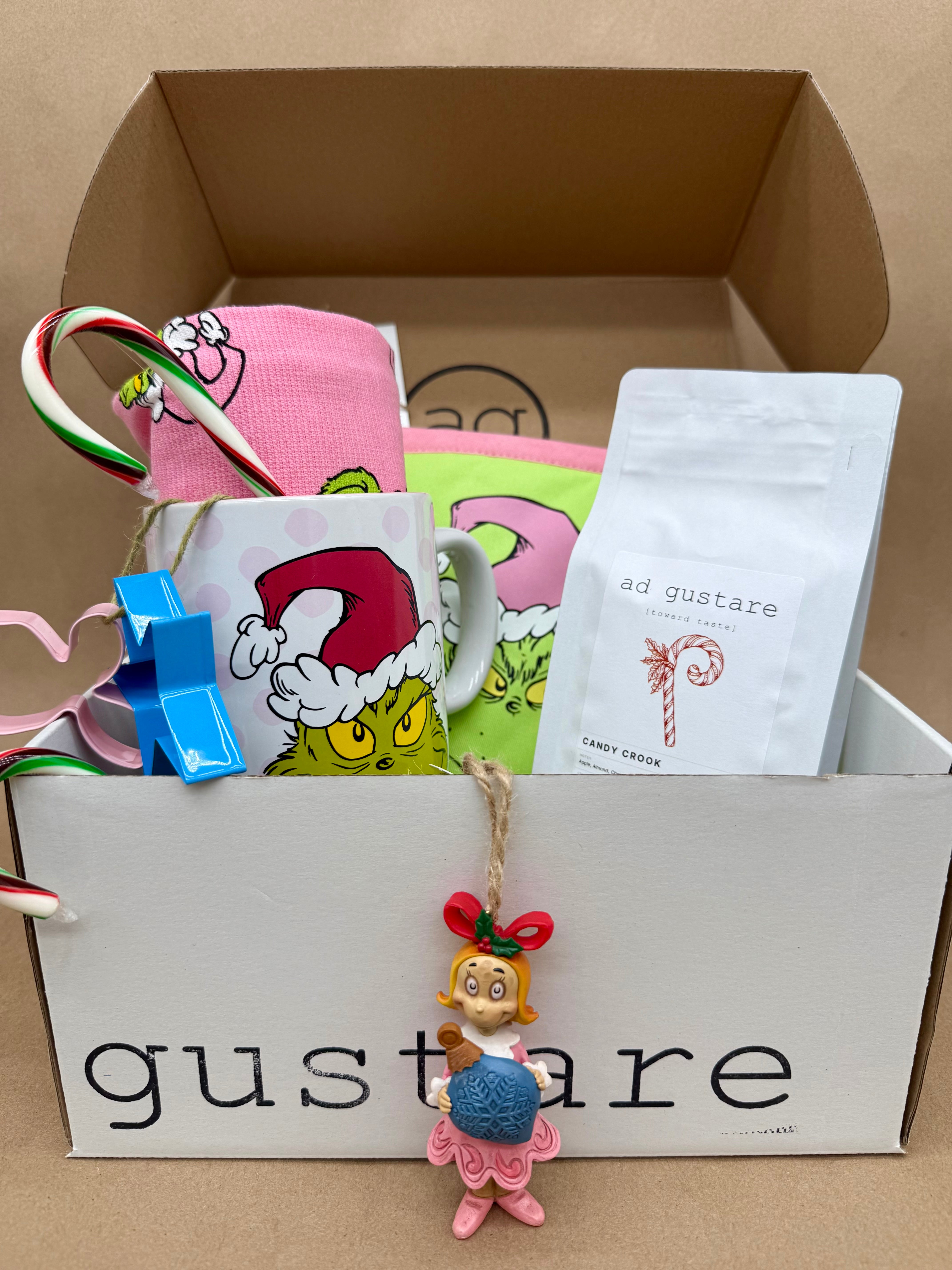 Box of 'gustare' with a mug, candy cane, and other items on a beige background